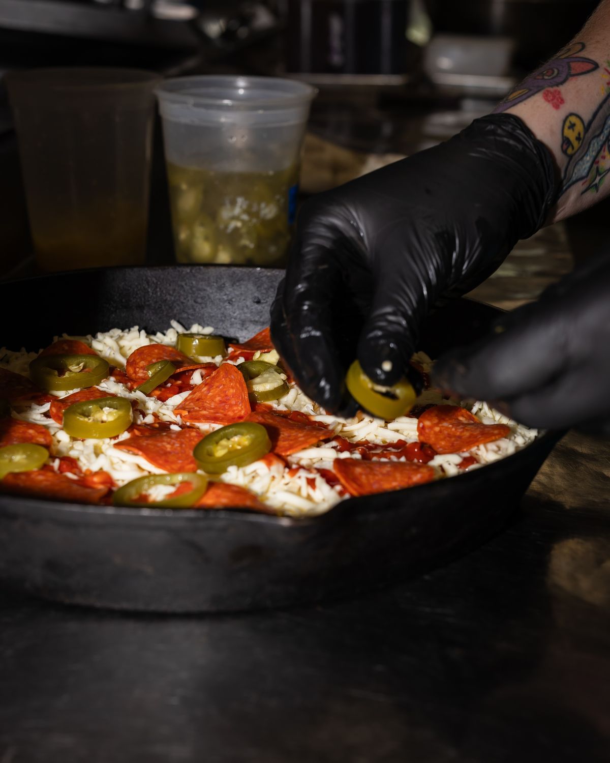Topping a pepperoni and jalapeno pizza in cast iron